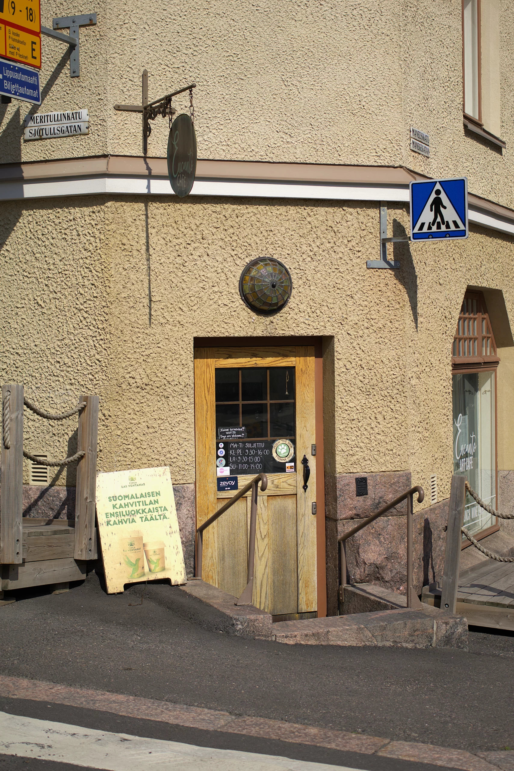 Katunäkymä Encanto Art Cafen ulko-ovesta, ovi on alempana katutasusta, siihen johtaa portaat sekä kaiteet
